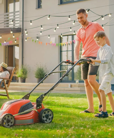 Father and son mowing the lawn together in a sunny backyard